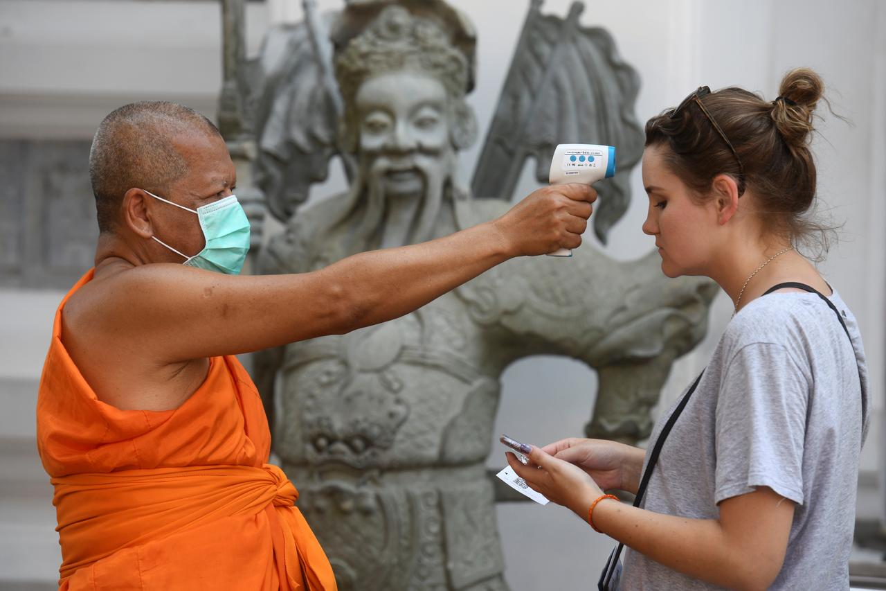Таиландда ибодатхонага келган ташрифчининг ҳароратини ўлчаётган будда роҳиби.