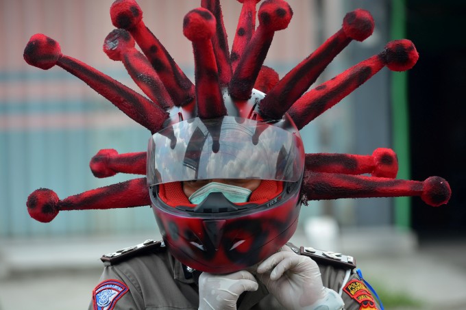 Индонезиянинг Шарқий Ява провинциясида коронавирус инфекциясига қарши тарғибот ишлари доирасида бошига вирус шаклидаги шлем кийган полиция ходими.