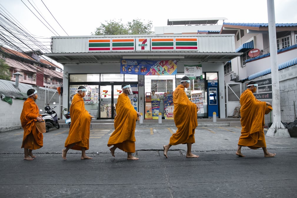 Бангкокда ниқоб таққан буддист монахлари эҳсон йиғгани бозорга кетмоқда.