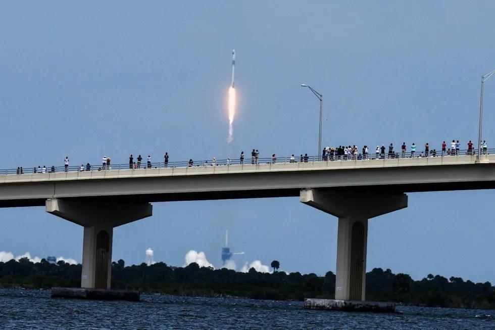 Одамлар SpaceX Falcon 9 ракетасини 2020 йил 30 майда Флорида штатининг Титевил шаҳрида Кейп-Канавералдан учишини томоша қилиш учун Мах Brеwеr кўпригига йиғилмоқда.