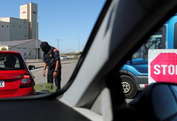 Полиция ходими Испаниянинг Лерида шаҳрига автомобилида саёҳат қилиш учун келаётганларнинг ҳужжатларини текширмоқда.
