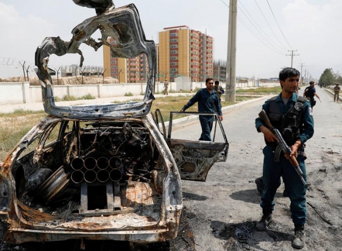 Афғон полициячилари жангарилар томонидан ракета учирилган автомобилни текширмоқда.
