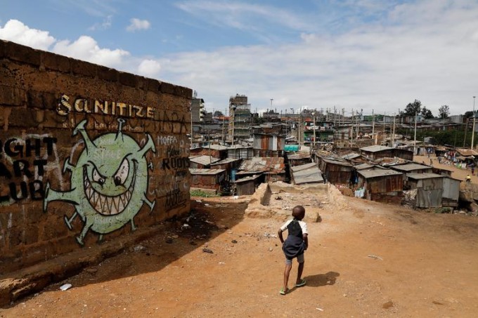 Кениянинг Найроби шаҳрида коронавирус касаллигига қарши курашни тарғиб қилувчи граффити олдида юрган болакай.
