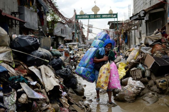 Филиппиннинг Метро Манила ҳудудидаги «Вамко» тайфуни оқибатида вайронага айланган ҳудуд ичида юрган ёстиқ ва матрас сотувчиси.