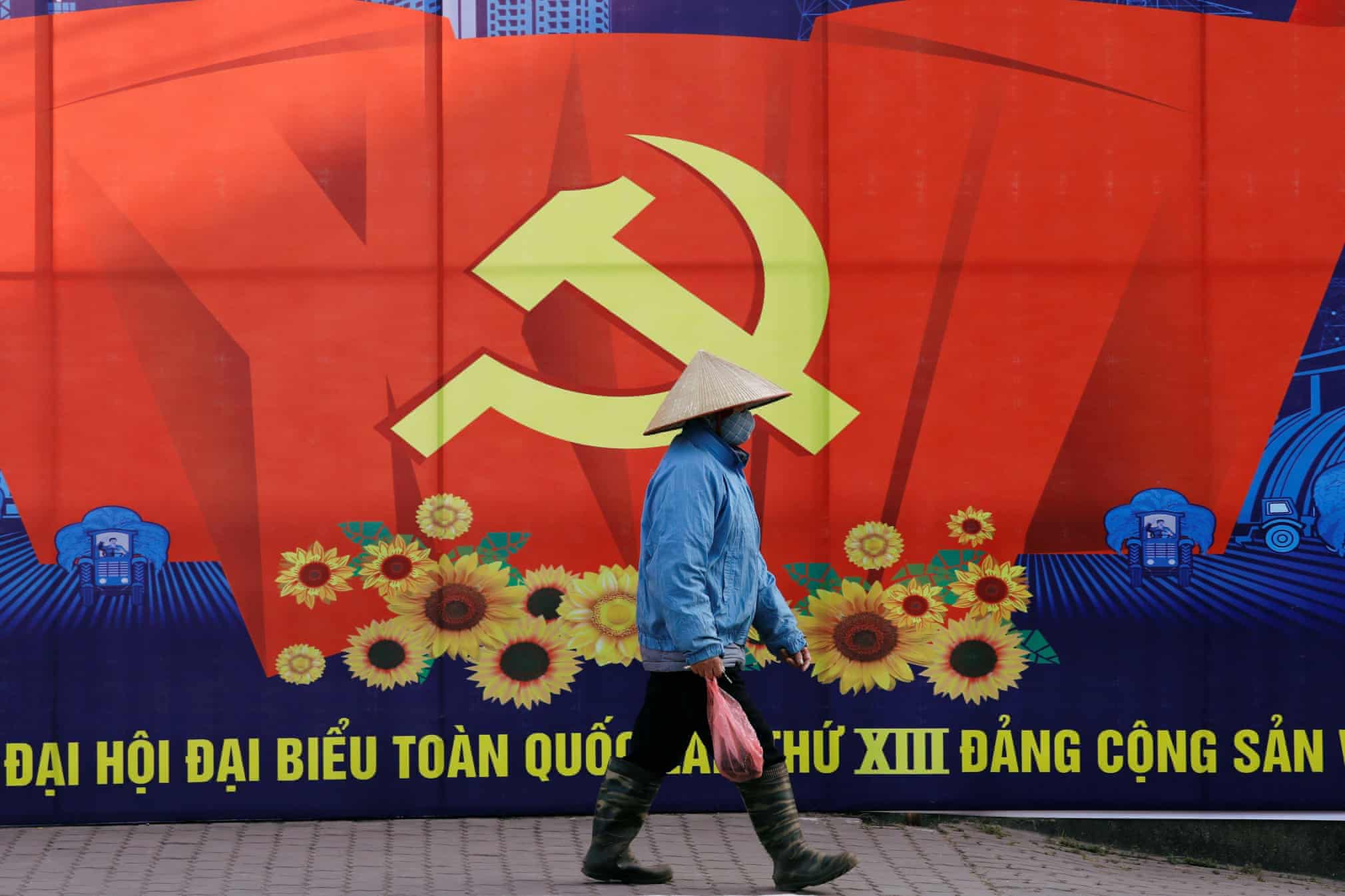 Вьетнамнинг Ханой шаҳрида Вьетнам Коммунистик партиясининг 13-миллий конгресси плакати ёнидан ўтиб бораётган одам.
