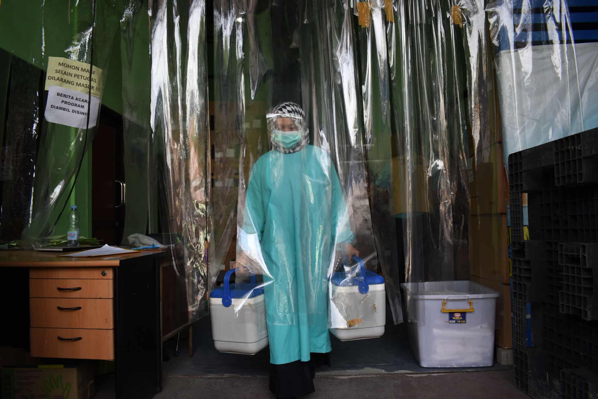 Индонезиянинг Бандунг ҳудудида музлаткичдан COVID-19’га қарши вакциналарни олаётган тиббиёт ходими.