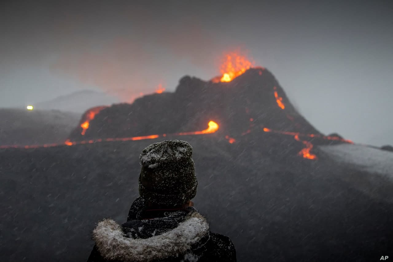 Исландиянинг Рейкянес ярим оролида уйғонган вулқондан оқиб чиқаётган лавани кузатаётган эркак.