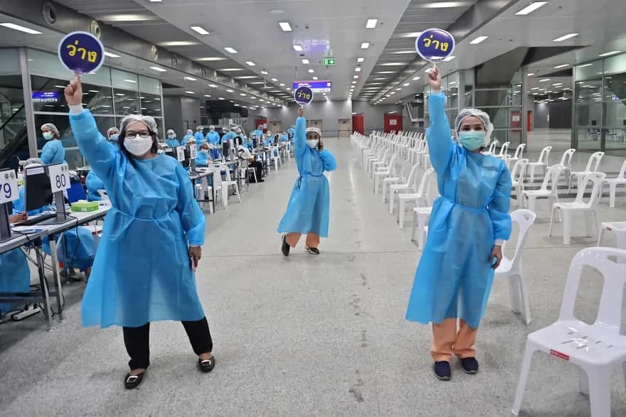 Тиббиёт ходимлари одамларни Бангкокдаги Банг Суэ марказий станциясида коронавирусга қарши CoronaVac вакцинасини олишга чақирмоқда.