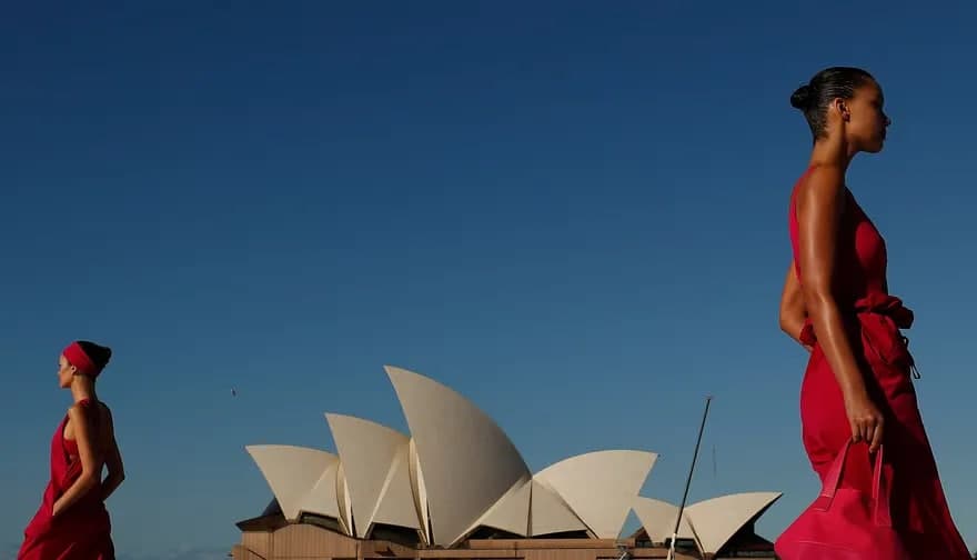 Австралиядаги мода ҳафталиги пайтида Сидней Опера театри фонида ўрнатилган подиумда юрган моделлар.