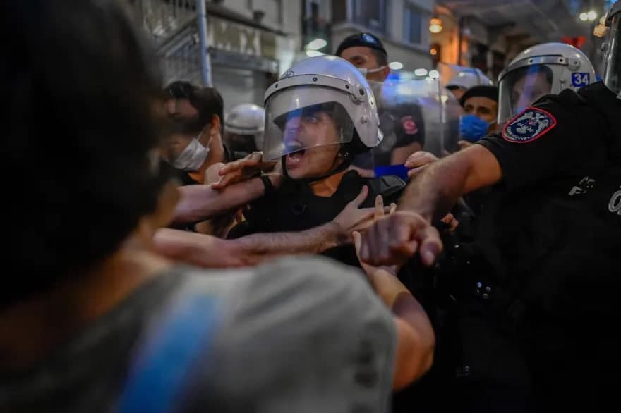 Туркиянинг Аёллар ҳуқуқларини ҳимоя қилиш бўйича Истанбул конвенциясидан чиқиш қарорига қарши митинг пайтида намойишчилар билан тўқнашган полициячи.