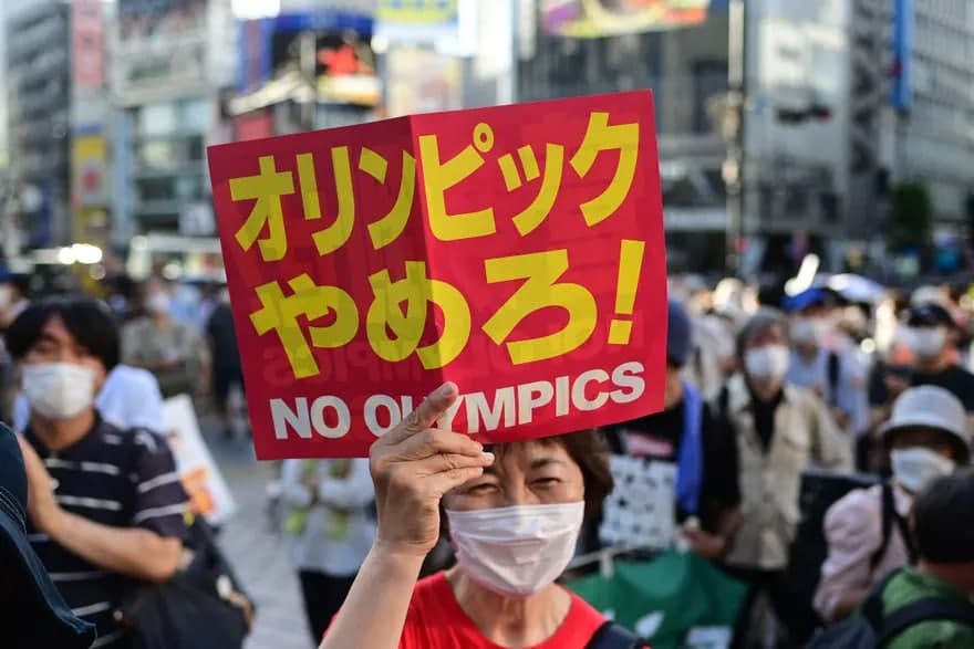 Токио—2020 Олимпия ўйинларини ўтказишга қарши намойишга чиққан аёл.