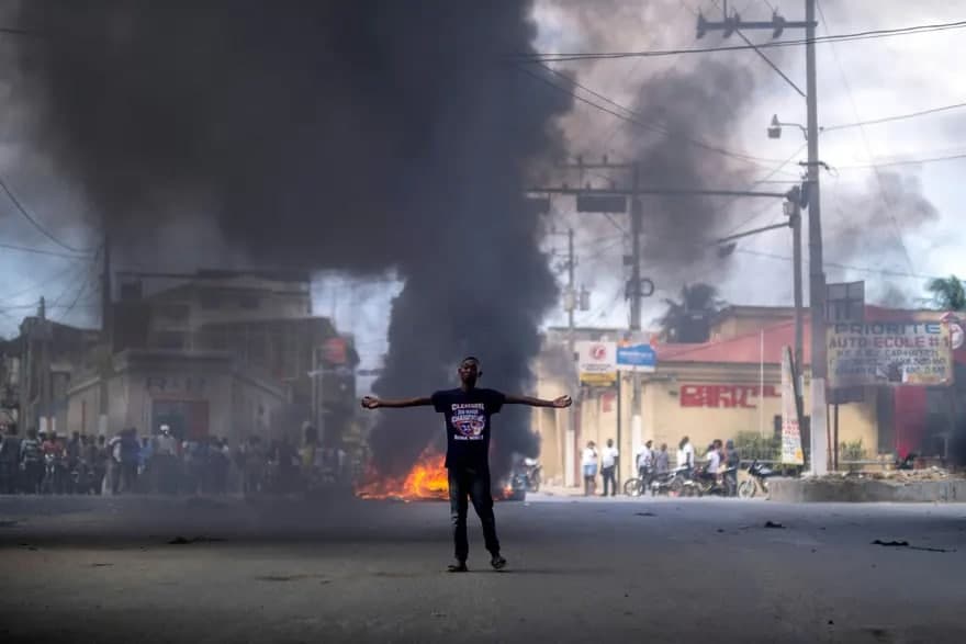 Гаити президенти Жовенель Моизнинг ўлдирилишига қарши намойиш пайтида ёнаётган шиналар тўсиғи олдида турган йигит.