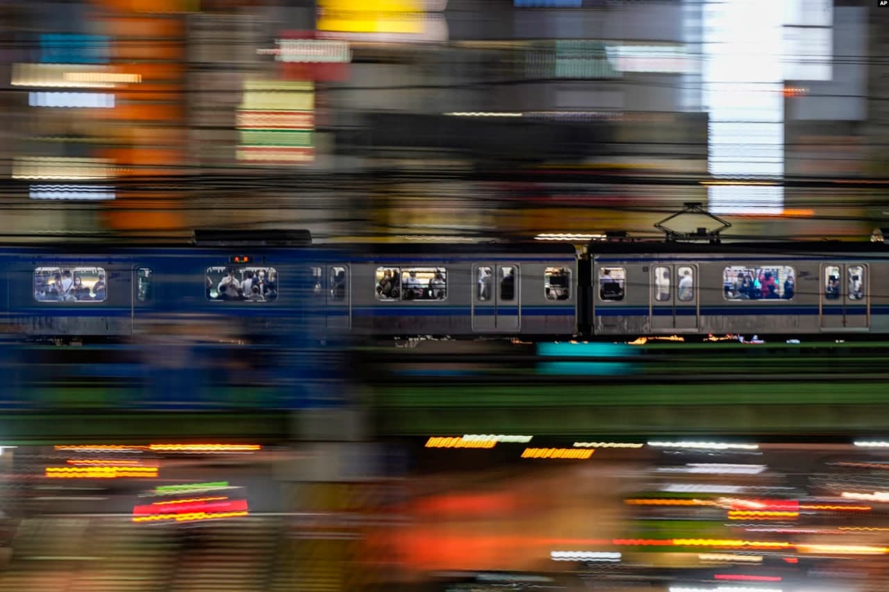 Токионинг Шинжуку округидан ўтаётган поезд ичидаги тиббий ниқоб кийган одамлар.