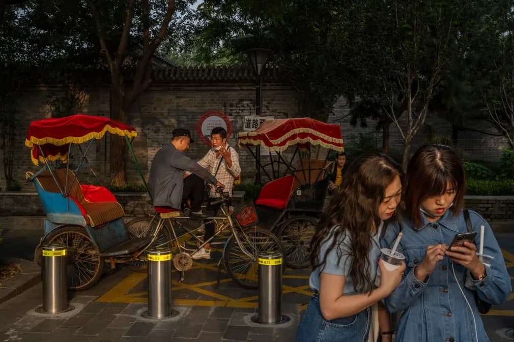 Пекиндаги Барабан минораси ёнида йўловчиларни кутиб суҳбатлашаётган велосипед ҳайдовчилари.