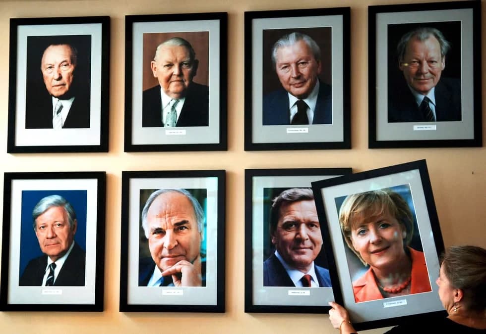 Германия Федератив Республикасининг биринчи аёл канцлерига айланган Ангела Меркелнинг портрети Берлиндаги KanzlerEck («Канцлер бурчаги») меҳмонхонасида аввалги ҳукумат раҳбарларининг портретлари ёнига илинмоқда. 2005 йил 23 ноябрь.