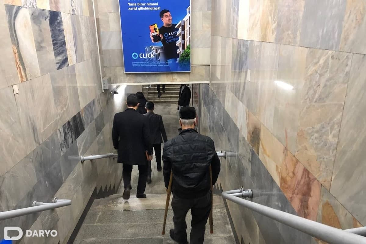 «Амир Темур» метро бекатидаги вестибюлдан қўлтиқтаёқда тушаётган отахон.
