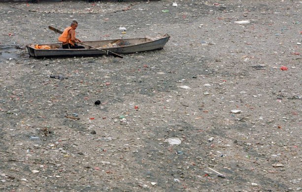 A Chinese worker on a boat tries to clea