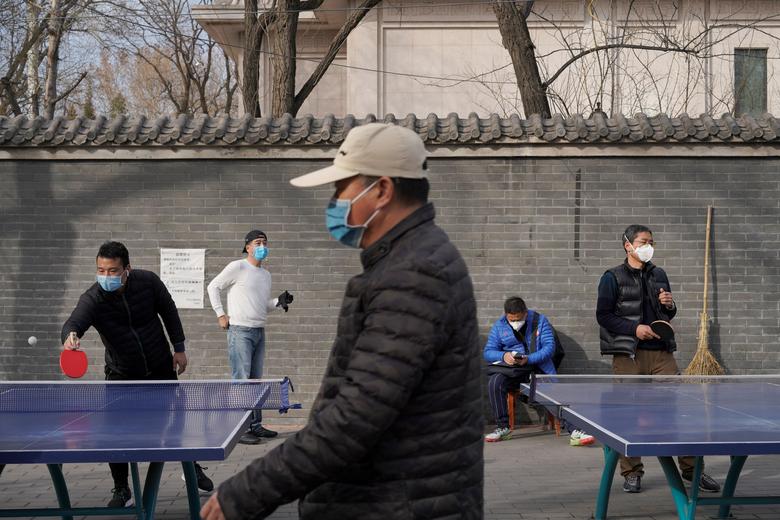 Пекиндаги паркда ниқоб тақиб олган одамлар стол тенниси ўйнамоқда.