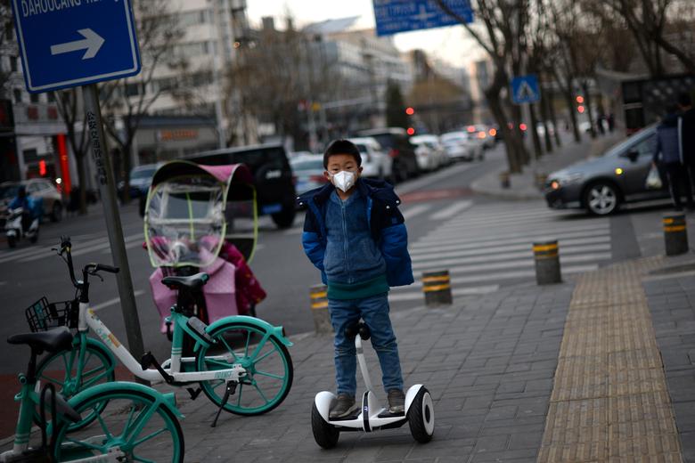Пекин кўчаларида скутер учаётган ниқоб таққан бола.