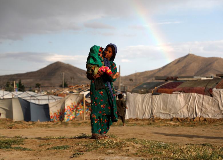 Kobul chetidagi qochoqlar lagerida bola ko‘tarib olgan qiz. <em>2019-yil, 20-iyun.</em>