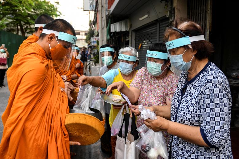 Bangkokda koronavirusdan himoyalanish uchun niqob taqib olgan buddist monaxlari ehson yig‘moqda.