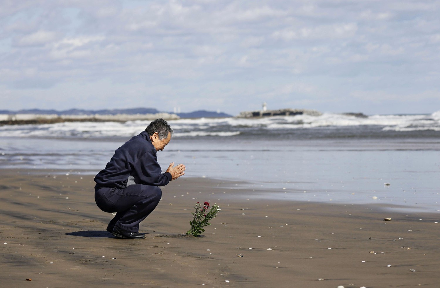 Фукусимада 2011 йил 11 март куни содир бўлган зилзила ва цунами оқибатида ҳалок бўлганларни хотирлаётган эркак.