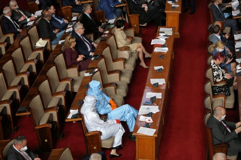 Bolgariyaning “Iroda” partiyasi rahbari Veselin Mareshkin va uning partiyasi deputati parlamentdagi debatlarda himoya kostyumida o‘tiribdi.