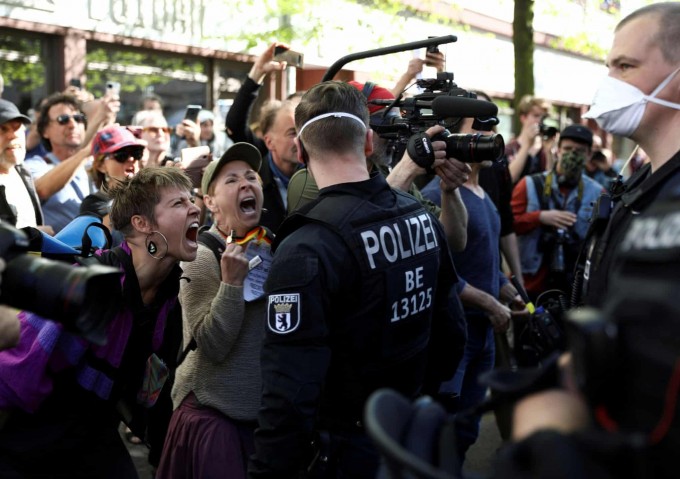 Berlinda shahar karantinga yopilganiga qarshi namoyishchilar politsiya xodimlariga baqirmoqda.