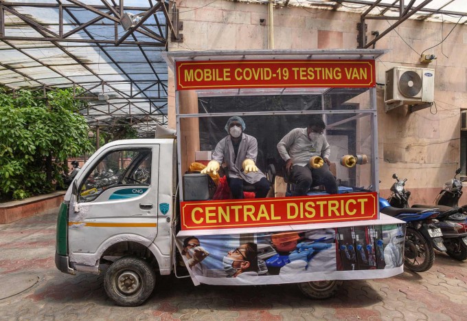 Hindistonning Nyu-Dehli shahrida furgonda koronavirus tahlili uchun test olishga hozirlanayotgan tibbiyot xodimlari.