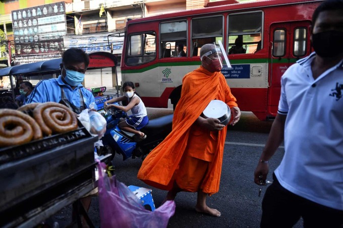 Tailandning Bangkok shahridagi bozorda buddaviy ruhoniy sadaqa so‘rab yuribdi.