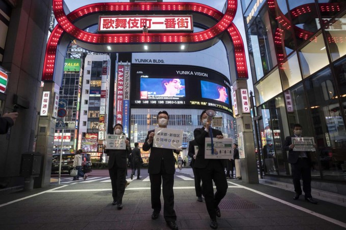 Tokio shahri ma’muriyati vakillari Kabukityo ko‘ngilochar tumanida odamlarni uylarida o‘tirishga chorlovchi plakatlar bilan yuribdi.