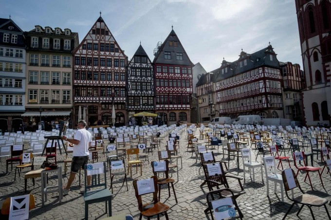 Germaniyaning Frankfurt shahrida koronavirus tufayli yopilgan bar va restoranlarning nomlari yozilgan bo‘sh stullar Ryomerberg maydoniga norozilik sifatida olib chiqilgan.