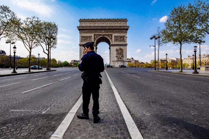 Коронавирус пандемияси туфайли бўшаб қолган Франциянинг Париж шаҳридаги Ғалаба дарвозаси ёнида ёлғиз юрган полиция ходими.