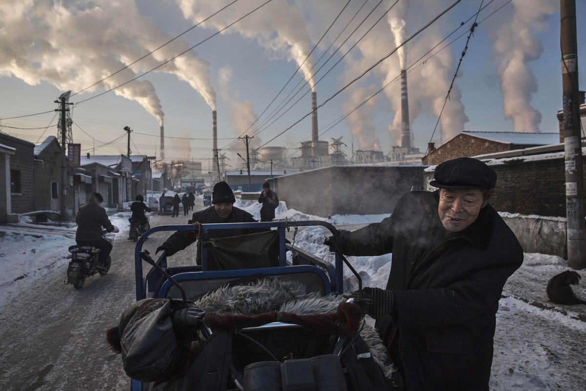 2015 йилнинг 26 ноябрида Хитойнинг Шаньси провинциясидаги кўмир электростанциясидан чиқаётган тутун. Эркаклар уч ғилдиракли велосипедни тортиб кетмоқда.