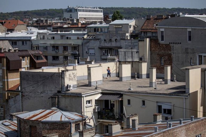 Serbiyaning Belgrad shahrida koronavirus tufayli tashqariga chiqa olmay, uylarning tomida sayr qilib yurgan ayol.
