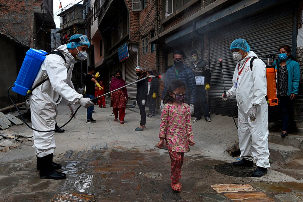 Nepal poytaxti Katmanduda tibbiyot xodimlari yosh qizaloqqa dezinfeksiya vositalarini sepmoqda.