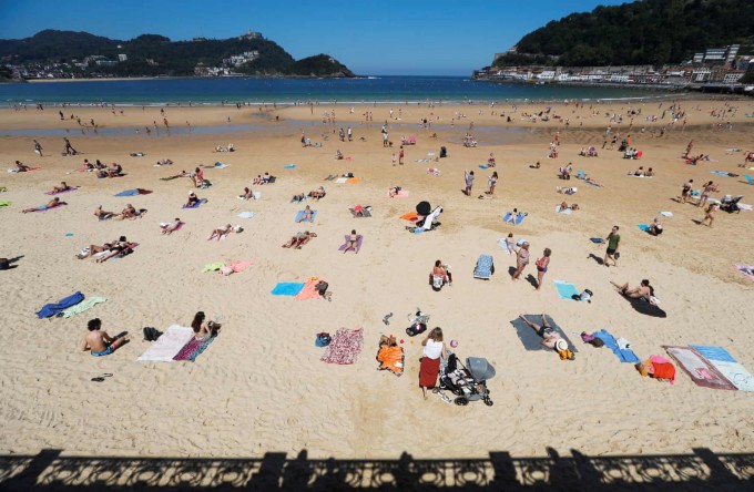Испаниянинг Сан-Себастьян шаҳридаги Ла-Конча пляжида тобланиб ётган одамлар.