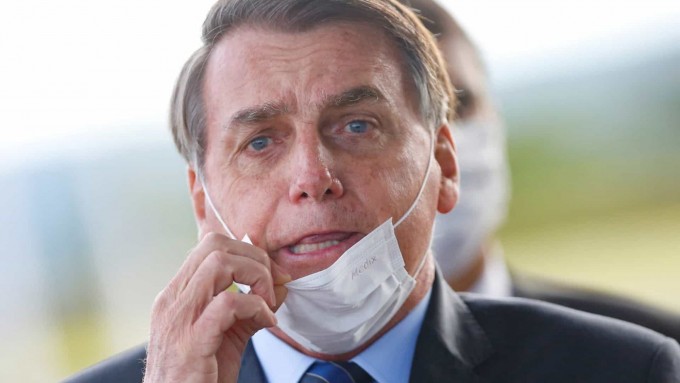 Braziliya prezidenti Jair Bolsonaro Alvorada saroyidan chiqa turib niqobini to‘g‘rilab olmoqda.