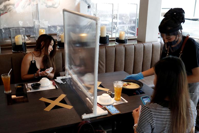 Таиланднинг Бангкок шаҳрида карантиндан кейин қайта очилган ресторанда овқатланаётган одамлар.