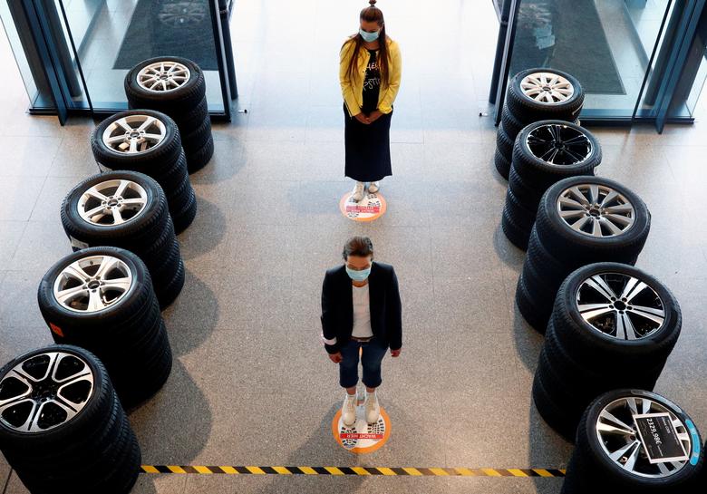 Belgiyaning Bryussel shahridagi Mercedes avtodilerida masofa saqlab turgan odamlar.