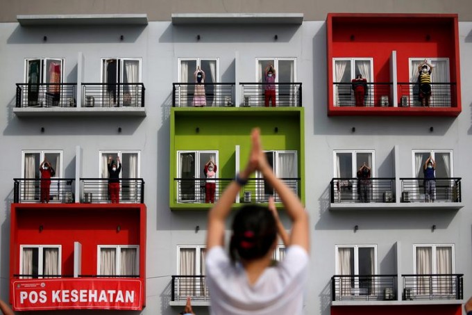 Indoneziyaning Jakarta shahrida karantin uyiga aylantirilgan o‘quv markazi balkonlarida mashq bajarayotgan bemorlar.