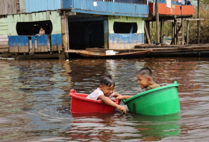 Peruning Ikitos shahrida Amazonka ko‘lidagi bandargohda bolalar plastik chelaklarda suzmoqda.
