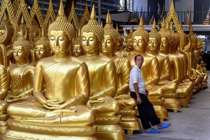 Таиланднинг Бангкок шаҳрида Будда ҳайкалчилари дўкони сотувчиси ҳайкалга суяниб турибди.