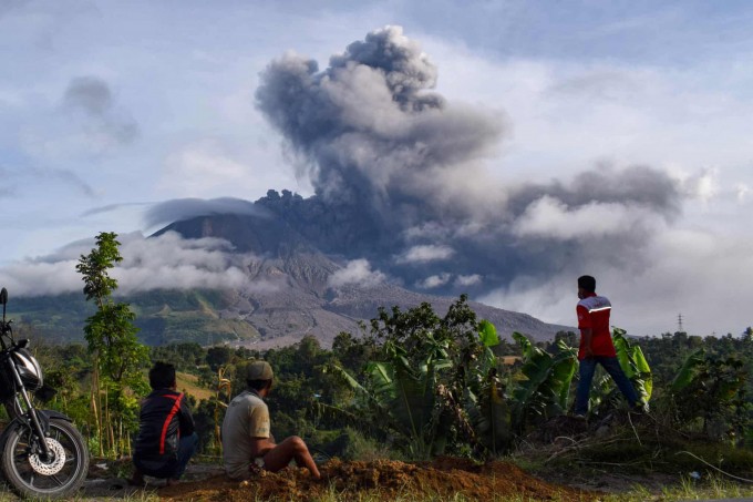 Indoneziyaning Karo hududida qishloq aholisi Sinabung vulqonining otilishini tomosha qilmoqda.