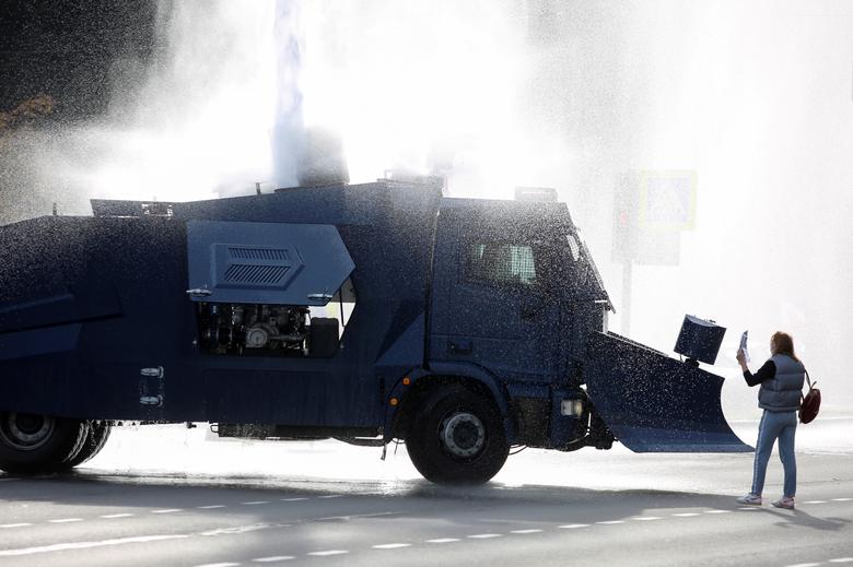 Minsk shahrida muxolifat vakili politsiya suvotar mashinasi oldida turibdi.