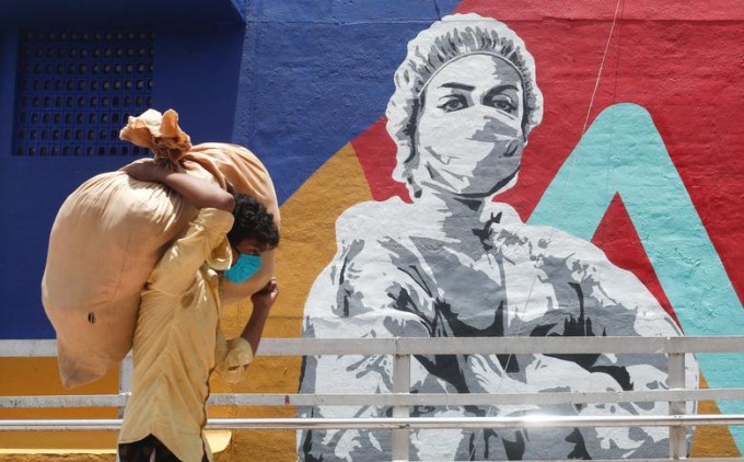 Мумбайда (Ҳиндистон) граффити ёнидан халта кўтариб ўтаётган киши.