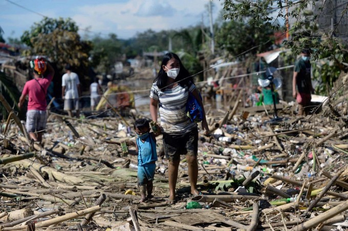 Филиппиннинг Родригес шаҳридаги Рисал провинциясида «Вамко» тайфуни келтирган талафотлар туфайли вайронага учраган уйлараро юрган она-бола.