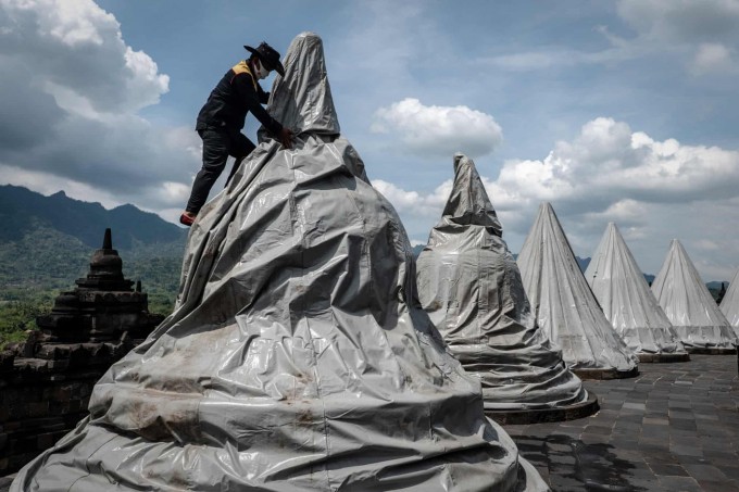 Indoneziyaning Magelang shahrida Borobudur ibodatxonasida vulqon kulidan zararlanmasligi uchun haykallarni yopib chiqayotgan xodim.