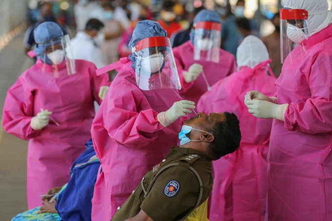 Shri-Lankaning Kolombo shahrida politsiya xodimi koronavirusga test topshirish uchun nazoratdan o‘tmoqda.