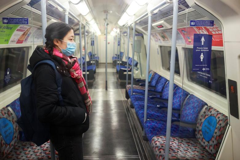 Лондонда деярли бўшаб қолган метро поезди ичида турган аёл.